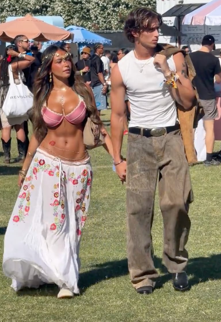 Boho chic festival fashion: woman in pink bra and floral skirt, man in white tank and brown pants.