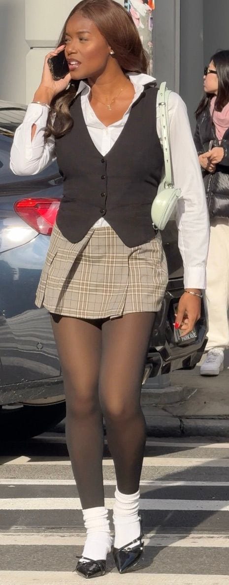 White shirt, black vest, and plaid mini skirt with black tights and patent mary janes.