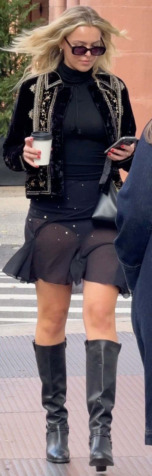 Black embroidered velvet jacket, turtleneck, sheer skirt, and tall boots.
