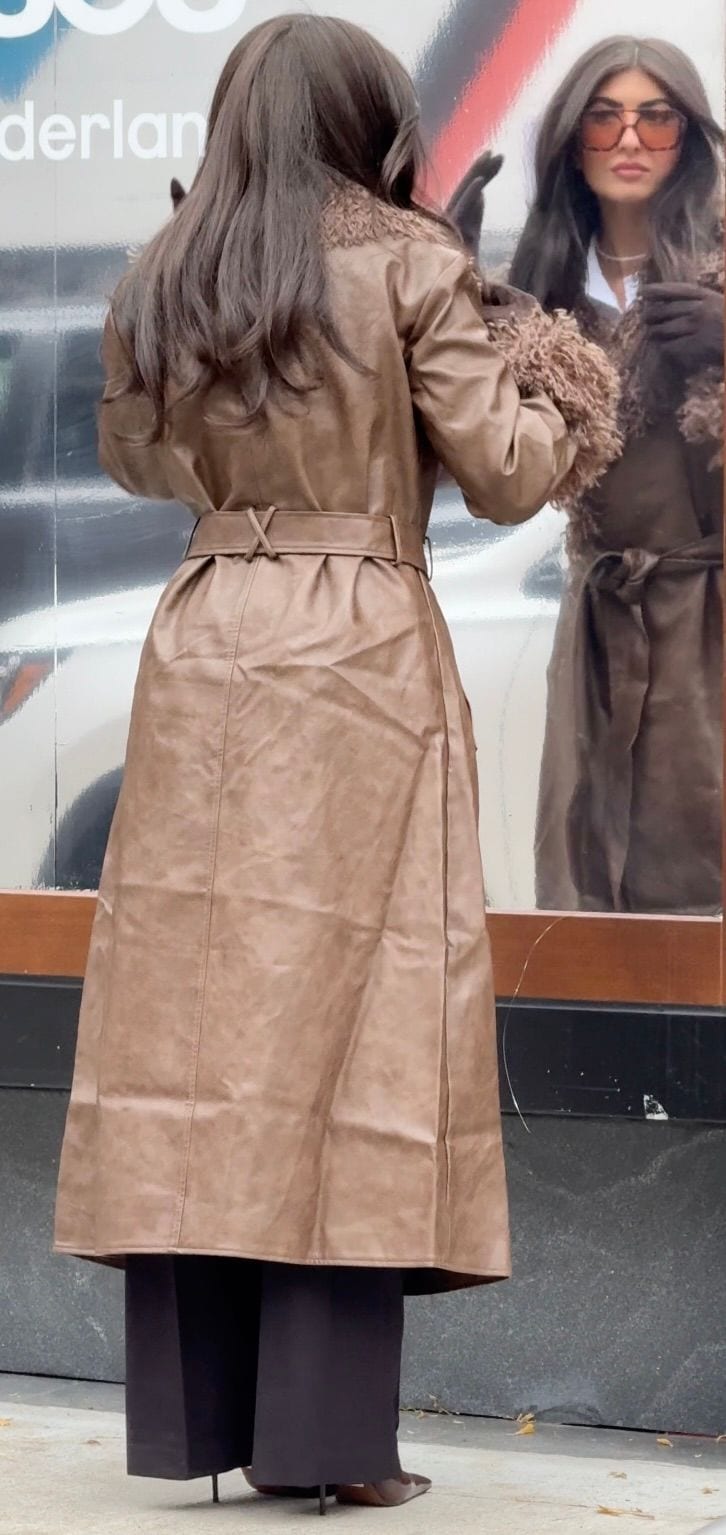 Brown leather trench coat with a fuzzy collar, styled with black wide-leg pants and pointed heels.