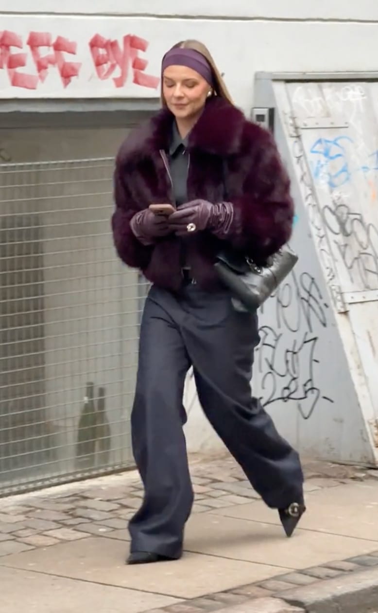 Burgundy fur coat, dark gray shirt, navy wide-leg pants, black heels, and purple headband.