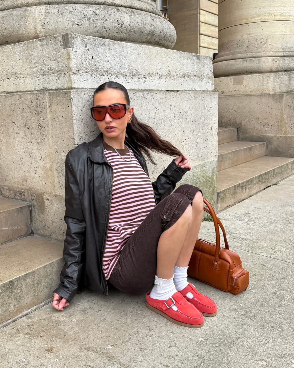 Black leather jacket, pink striped top, brown shorts, red loafers, and brown purse.