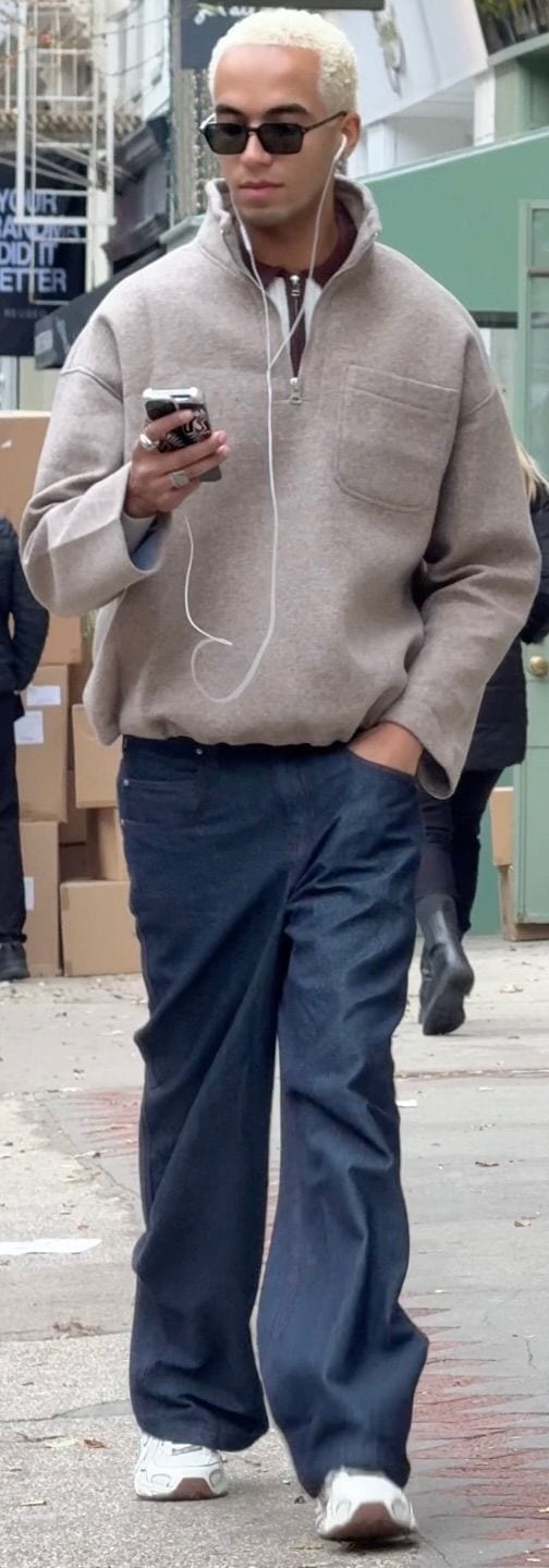 Khaki half-zip pullover, wide-leg dark wash jeans, white sneakers, and black sunglasses.