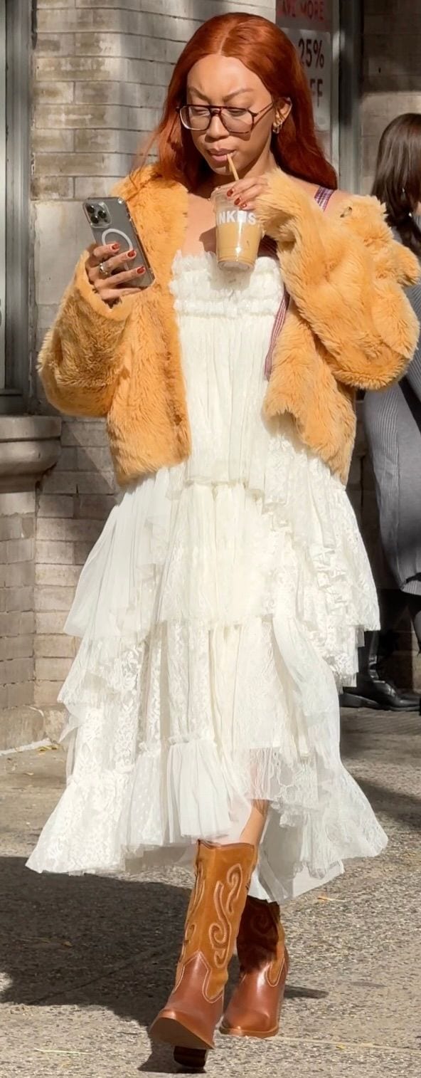 White tiered lace dress, cropped orange faux fur jacket, brown cowboy boots.