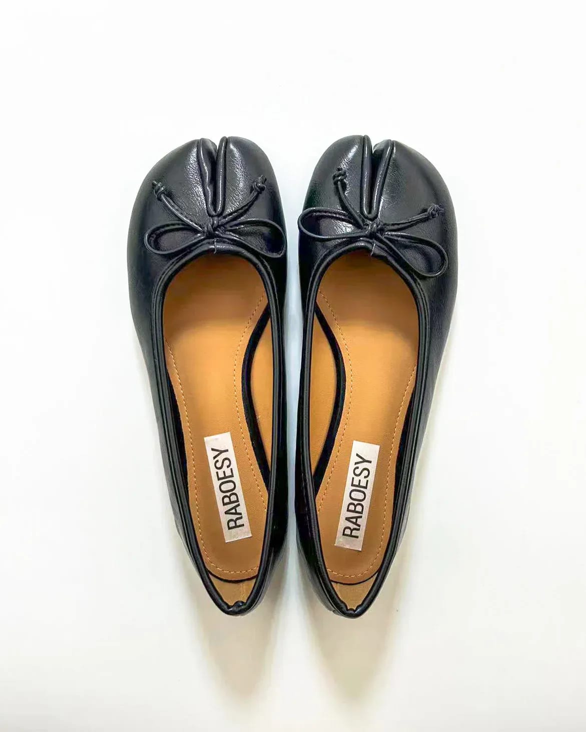 Black leather tabi toe ballet flats with bow detail.