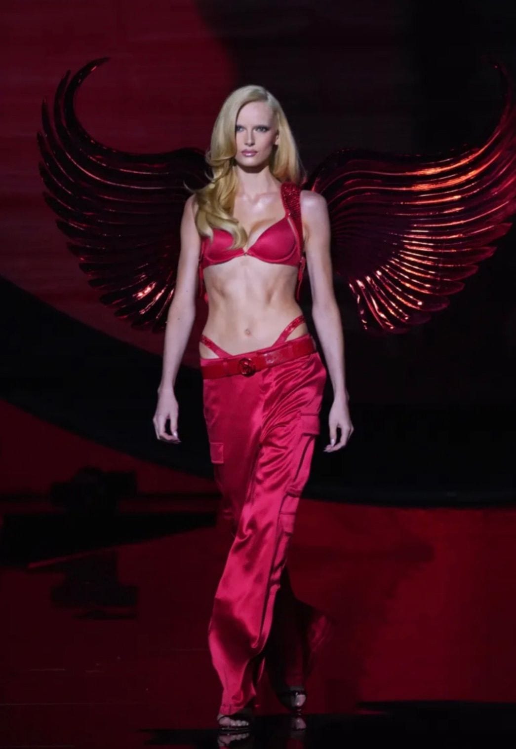 Red satin bra with matching high-waisted cargo pants and large red metallic wings.