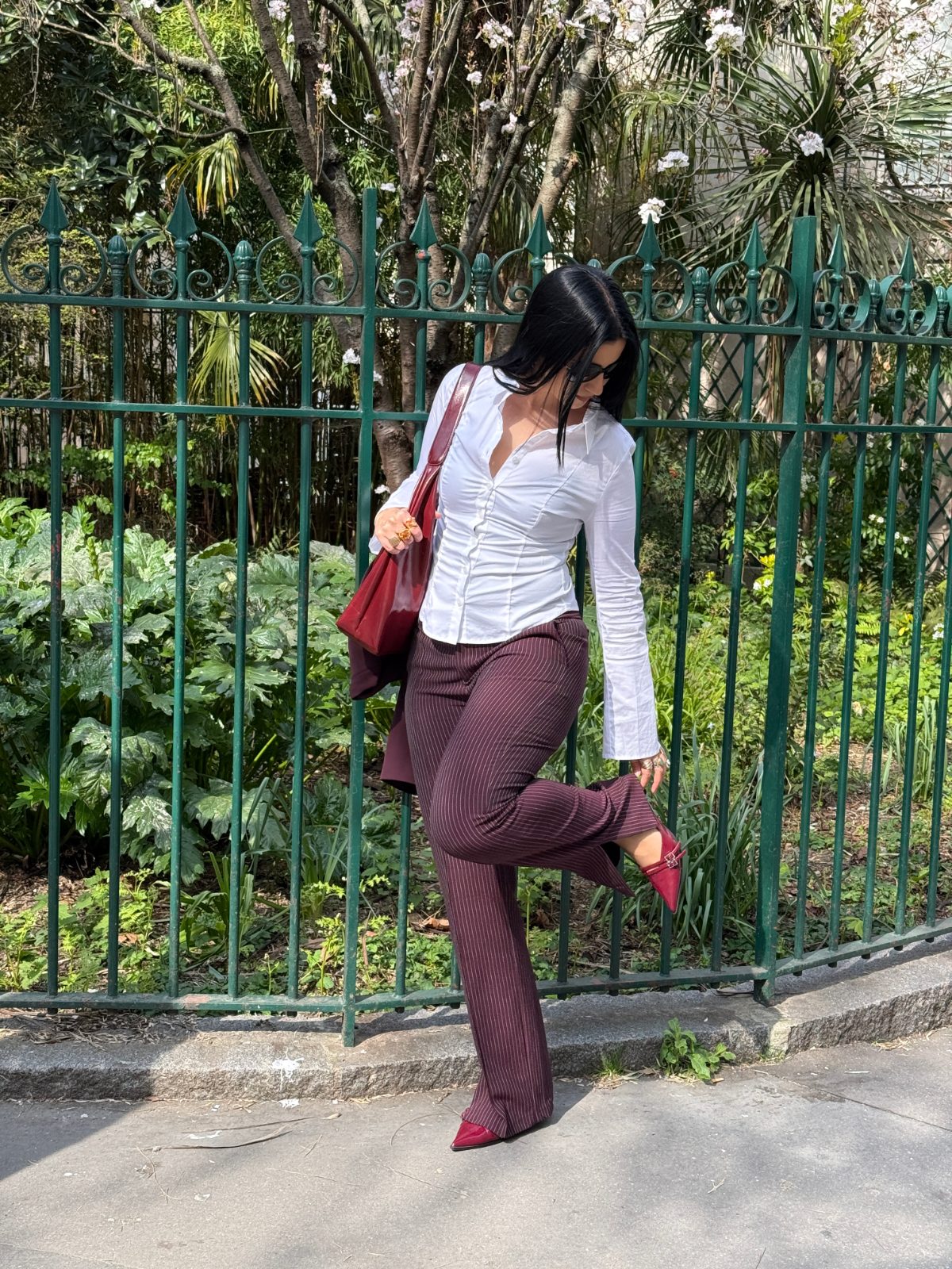 White collared blouse, pinstripe maroon pants, and red heels with a matching bag.