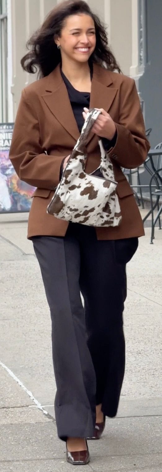 Brown blazer and black trousers paired with a cow-print bag and brown heels.