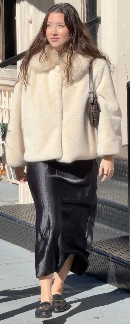 Cream faux fur coat, black satin skirt, and black loafers with a Fendi bag.