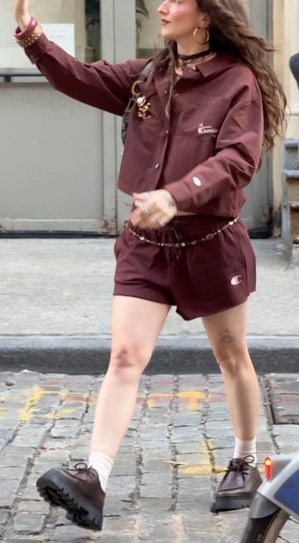 Brown cropped Champion shirt and matching shorts with a beaded chain belt and chunky shoes.