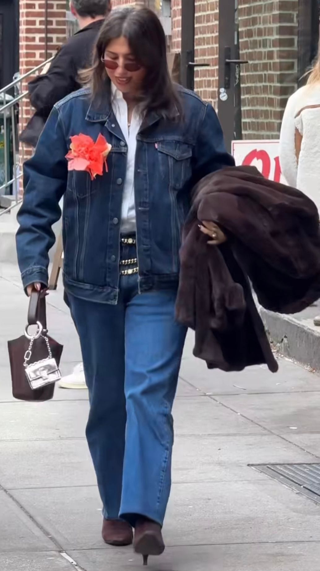 Denim jacket with orange flower, white shirt, chain belt, brown bag, mini silver bag, brown boots.