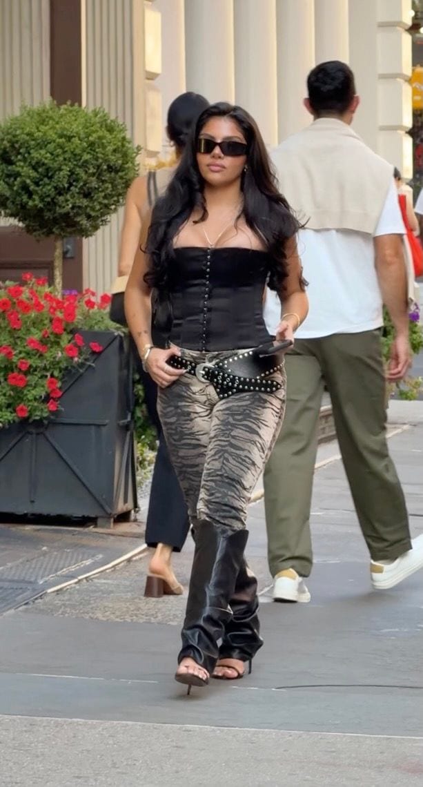 Black corset top, tiger-print pants, studded belt, black heels, and rectangular sunglasses.