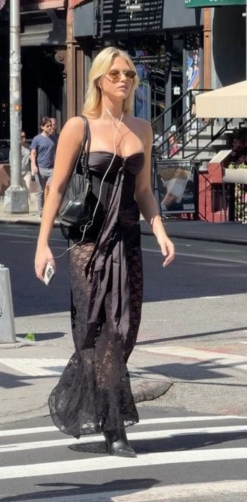 Black strapless corset top, sheer lace maxi skirt, and boots on city street.