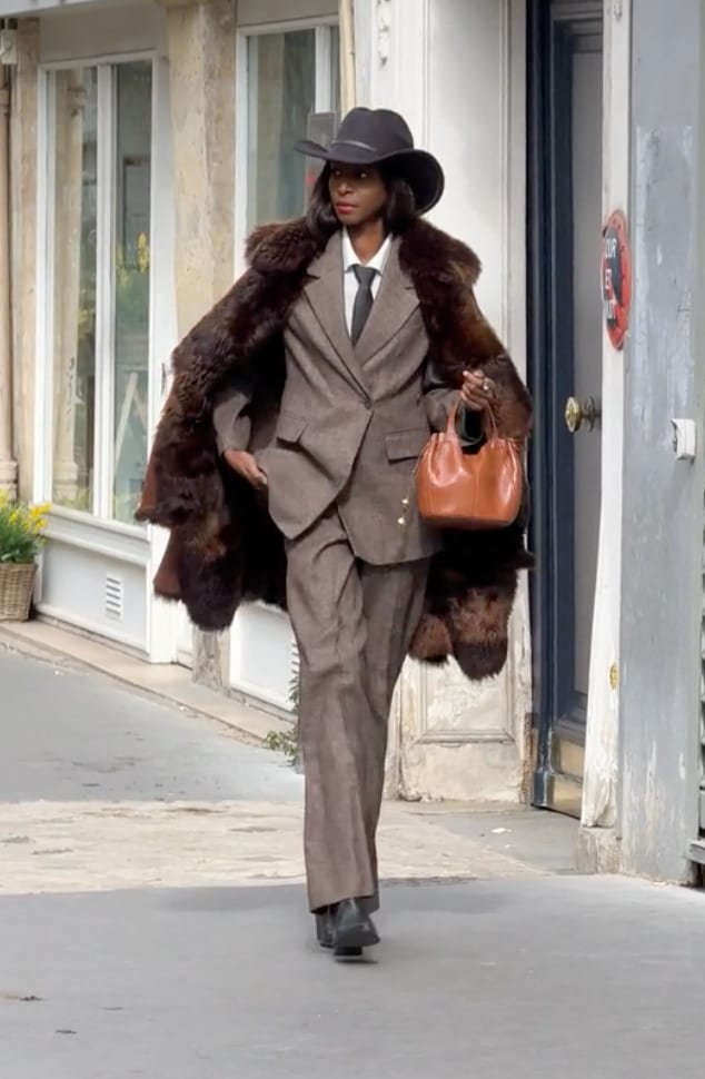 Brown suit with fur stole, black hat, and brown handbag.