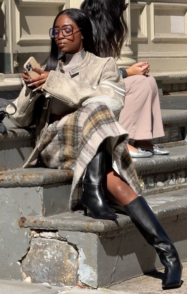 Grey leather jacket, plaid midi skirt, black knee-high boots, and glasses on a sunny day.