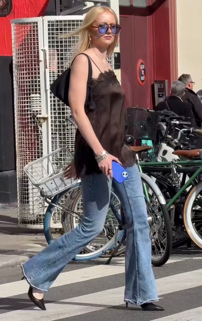 Brown satin lace camisole, flared jeans, black pointed heels, and blue sunglasses.