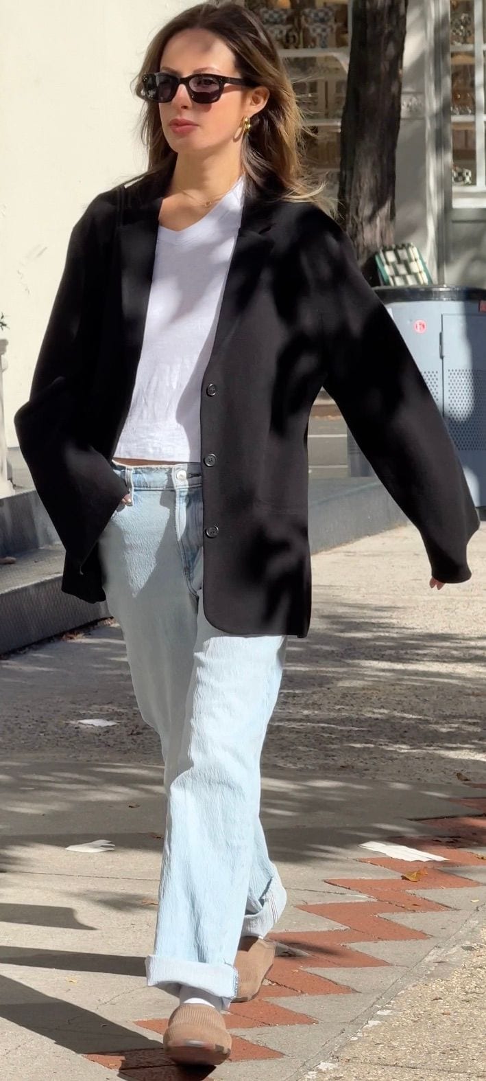 Black blazer, white crop top, light wash jeans, and brown slip-on shoes.