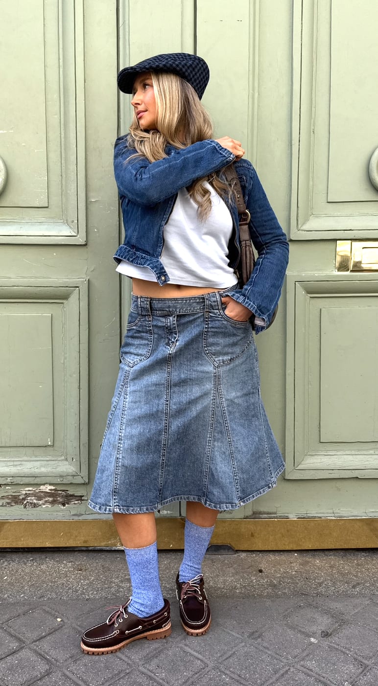 Denim jacket over white crop top, denim midi skirt, brown boat shoes, light blue socks.