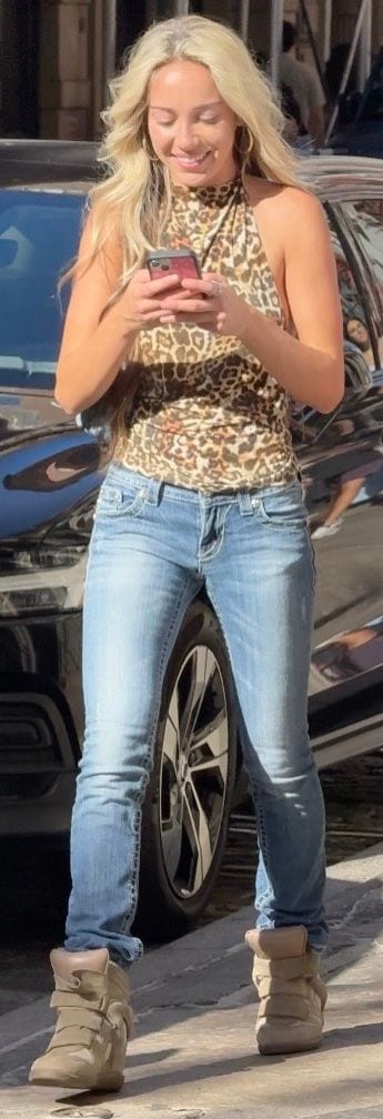 Leopard print halter top with light wash jeans and tan wedge sneakers.