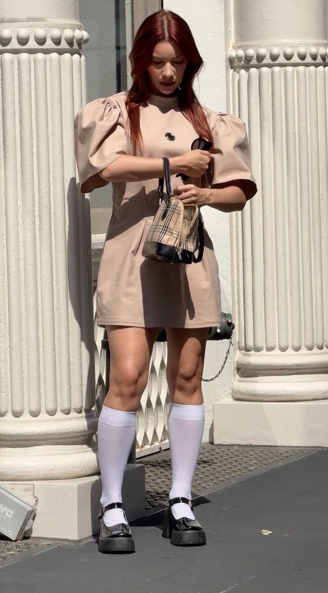 Beige puff-sleeve dress with eyelet, plaid handbag, white knee socks, and Mary Janes.