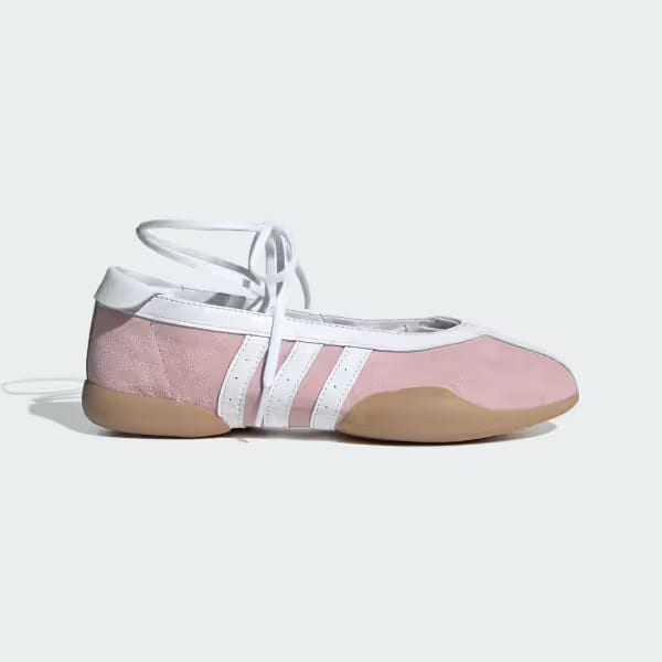 Pink ballet flat sneakers with white laces, white trim, white stripes, and tan sole.