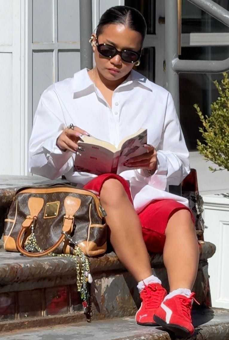 White oversized shirt, red shorts, red Puma sneakers, and a Louis Vuitton bag.