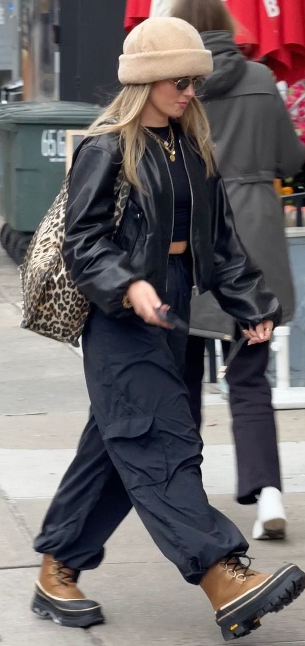 Beige beanie, black leather bomber jacket, black cargo pants, and tan combat boots.