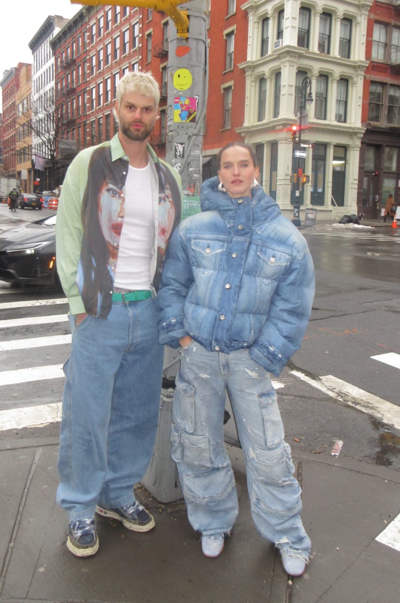 Light green shirt with face graphic, wide-leg jeans, denim puffer jacket, distressed cargo pants.