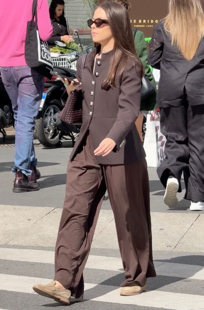Brown button-front jacket with matching wide-leg pants, beige loafers, and cat-eye sunglasses.