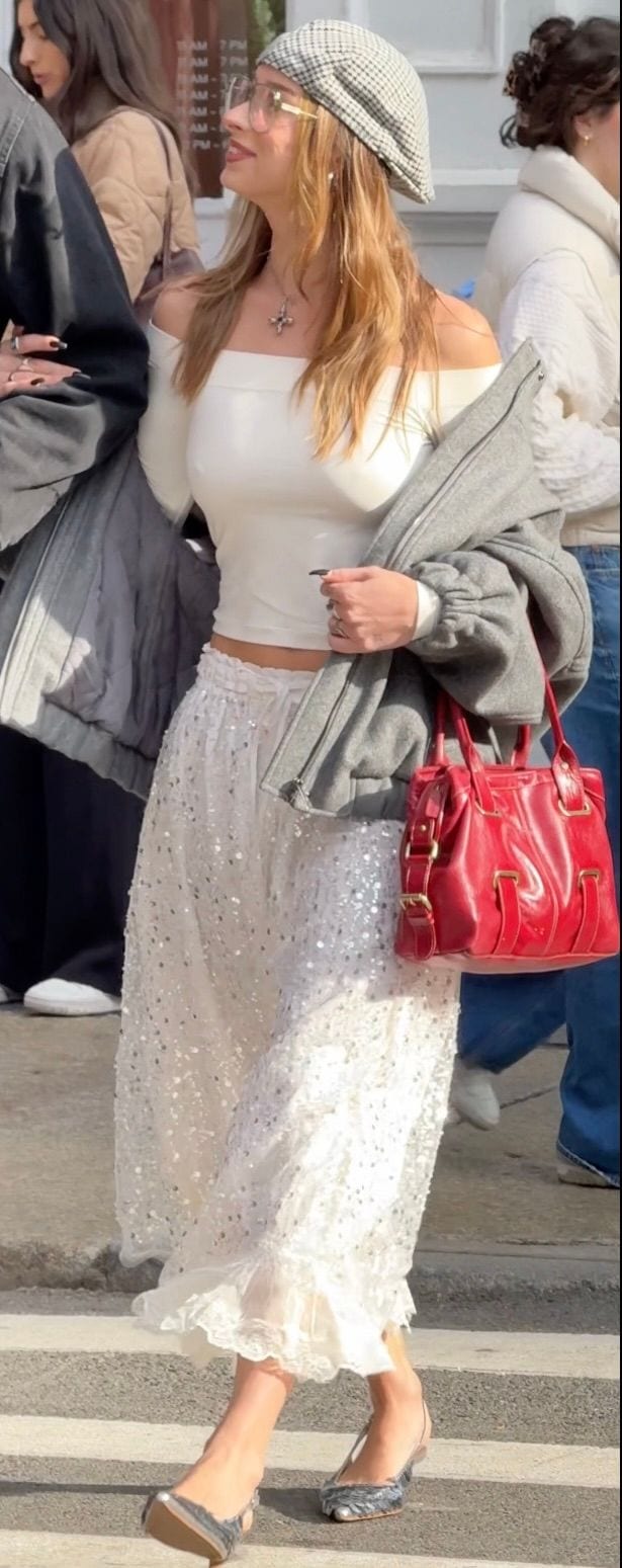 White off-shoulder top, sequin skirt, checkered beret, gray jacket, red handbag, and slingback heels.
