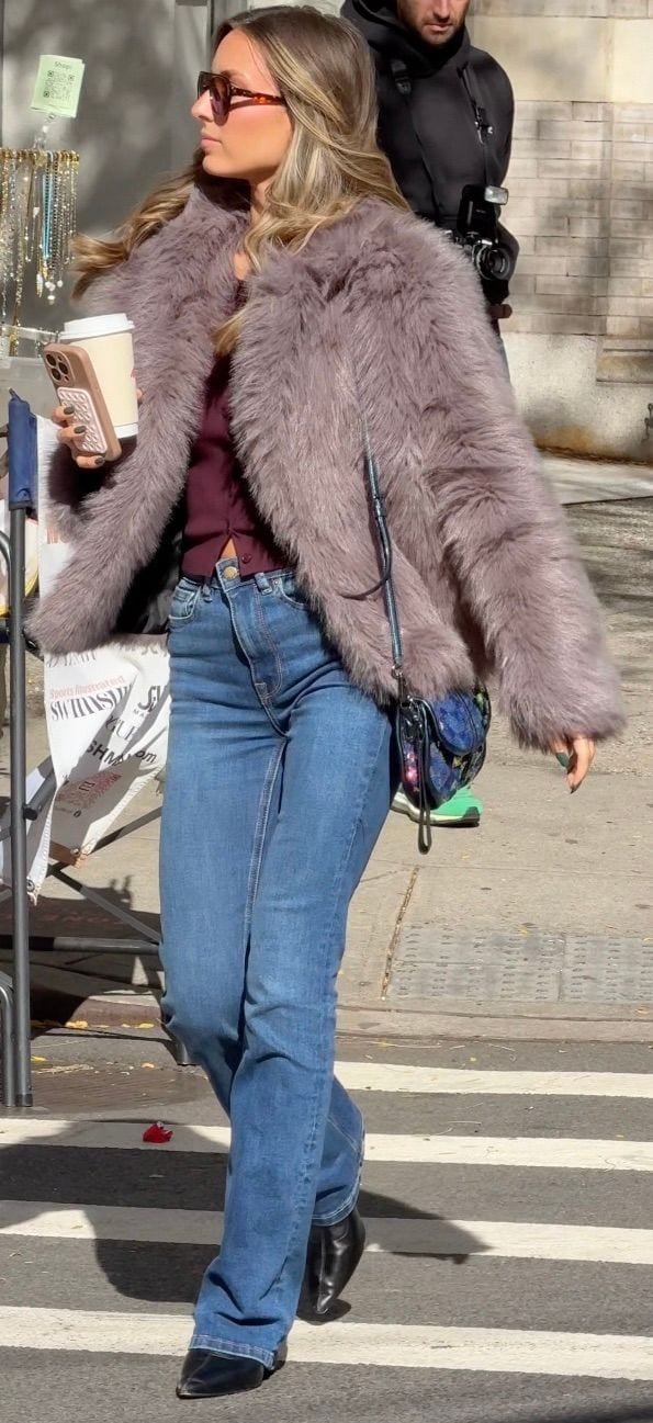 Light purple faux fur coat, maroon top, blue jeans, black boots, and sunglasses.