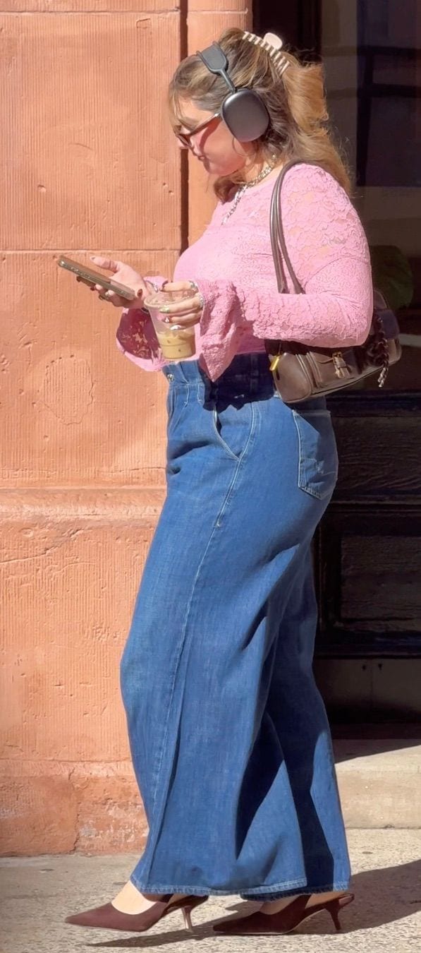 Pink lace long-sleeve top, wide-leg jeans, brown kitten heels, headphones, and a handbag.