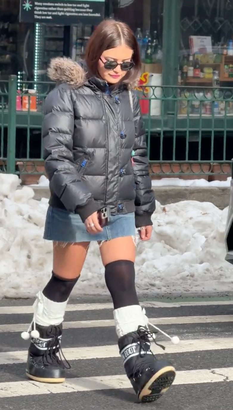 Black puffer coat with fur hood, denim mini skirt, black thigh-high socks, and Moon Boots.