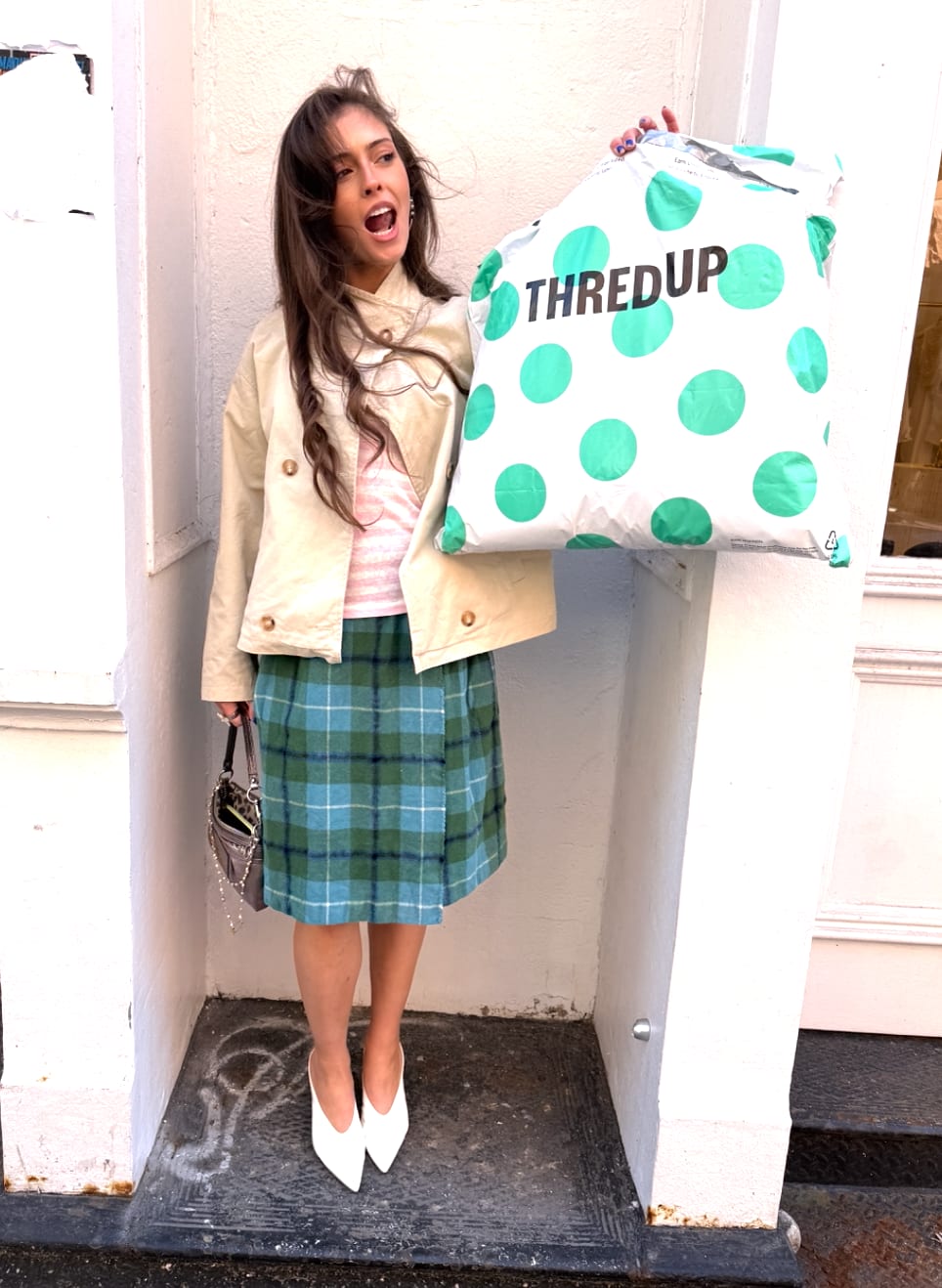 Beige jacket, striped top, green plaid skirt, white heels, holding a ThredUp bag.