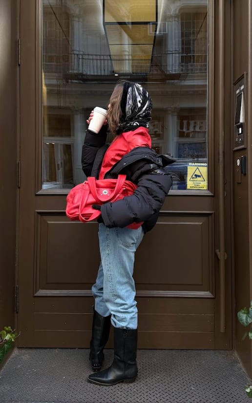 Red bomber jacket, black puffer, light blue jeans, black boots, red purse, and headscarf.