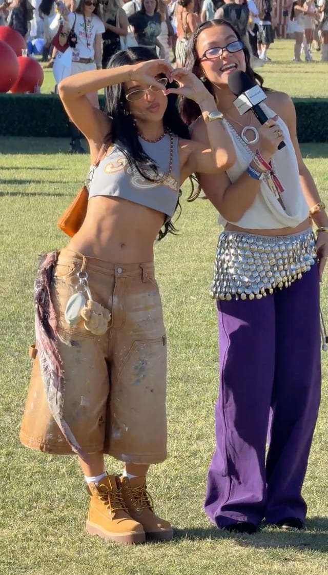 Festival fashion: Gray crop top, paint-splattered cargo pants, and a white draped top with a coin belt.