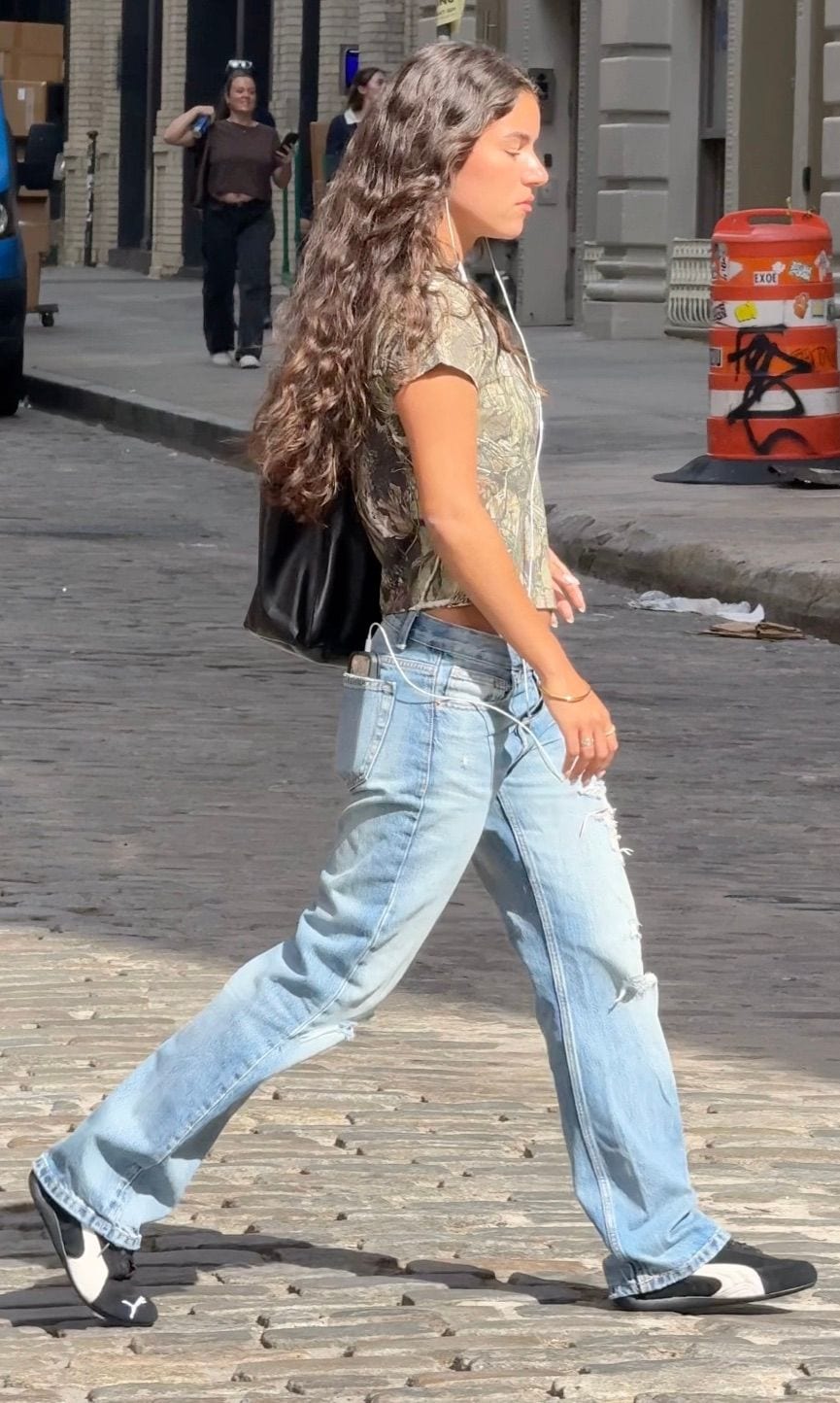 Camo crop top, ripped light wash jeans, and black and white sneakers on a city street.