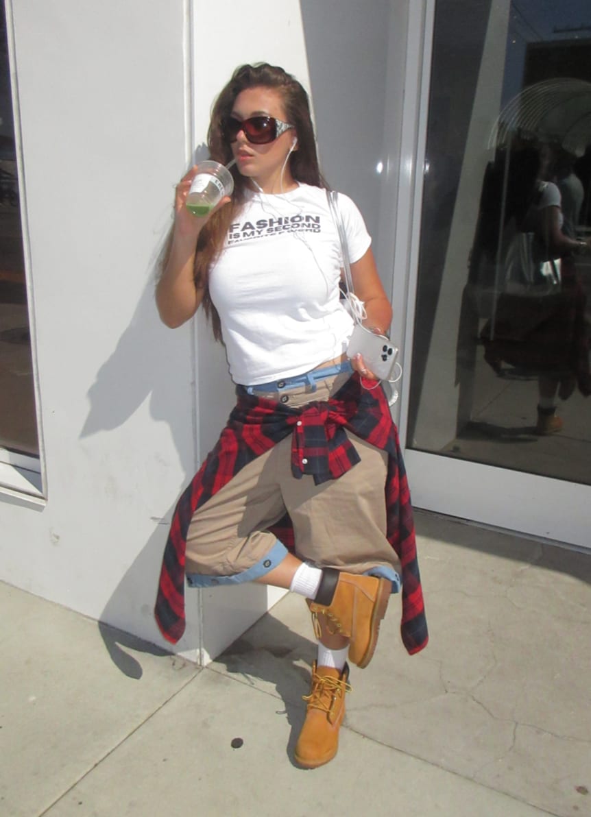 White t-shirt, khaki pants, red plaid shirt tied around waist, and tan work boots.