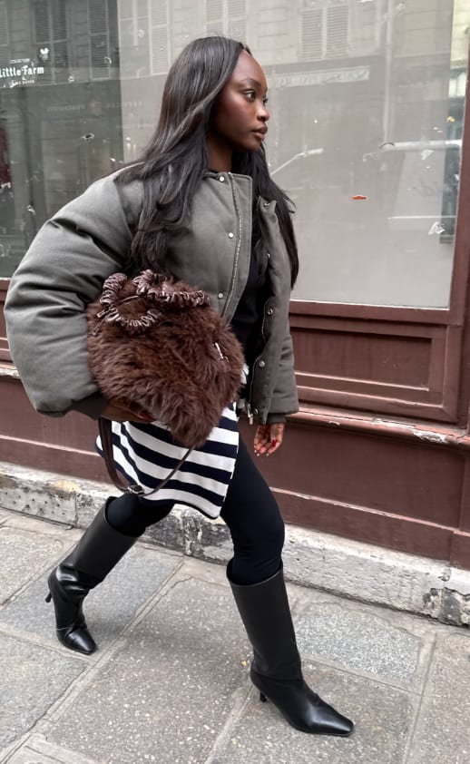 Olive green puffer jacket, black leggings, striped top, brown faux fur bag, and black boots.