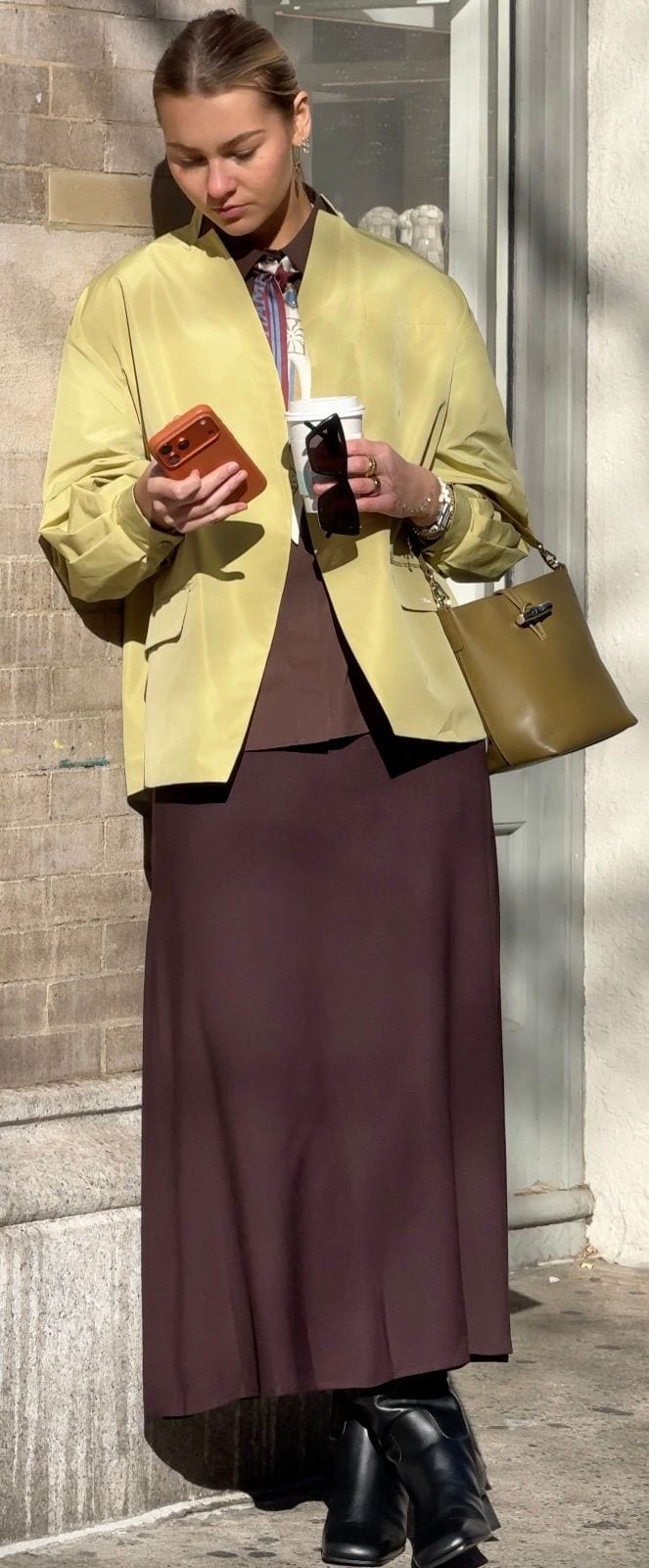 Lime green blazer, brown shirt with striped tie, brown maxi skirt, black boots, and olive green handbag.