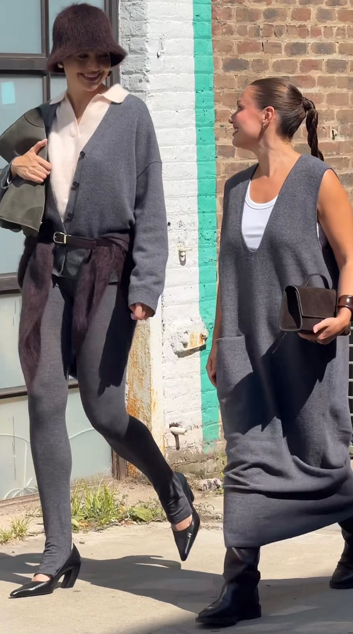Two women in gray knitwear outfits, one with a fur bucket hat and belt, the other a sleeveless dress.