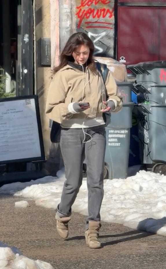Tan bomber jacket, grey jeans, and tan wedge sneakers on a snowy city street.