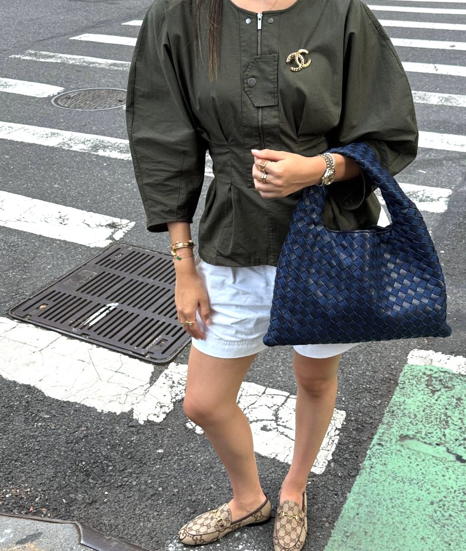 Olive utility top with white shorts, Gucci loafers, and a navy woven bag.
