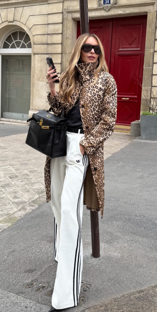 Leopard print trench coat, black top, white Adidas track pants, black bag, and sunglasses.