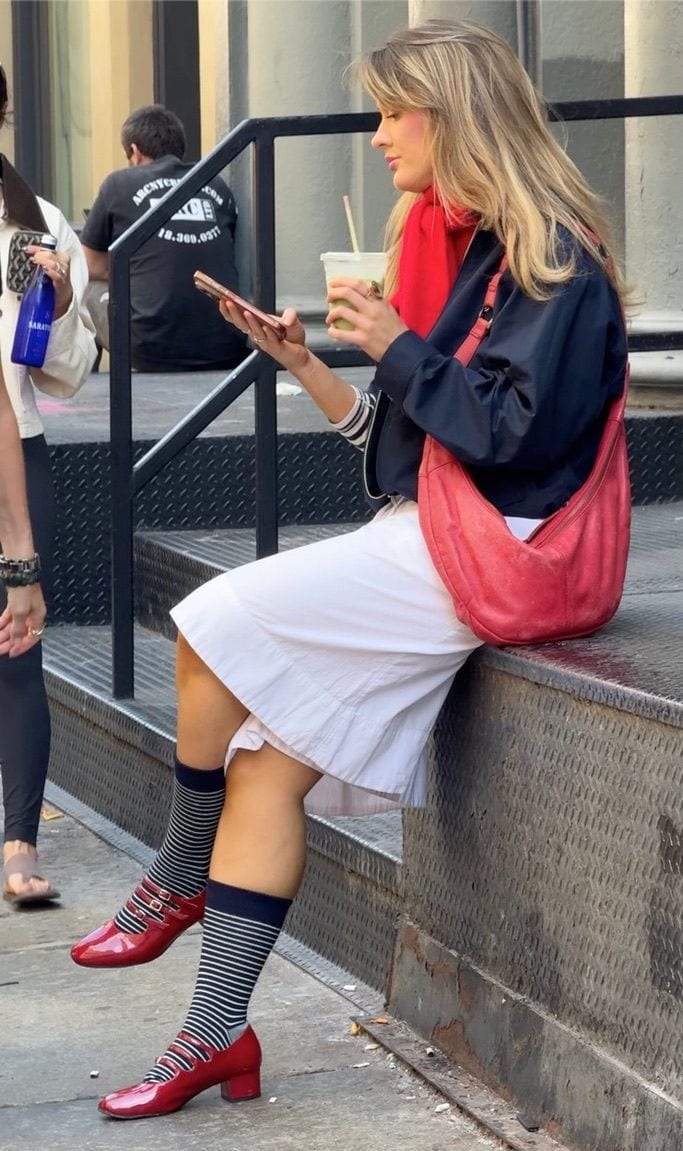 White dress, navy bomber jacket, red scarf & bag, striped socks, red Mary Jane shoes.