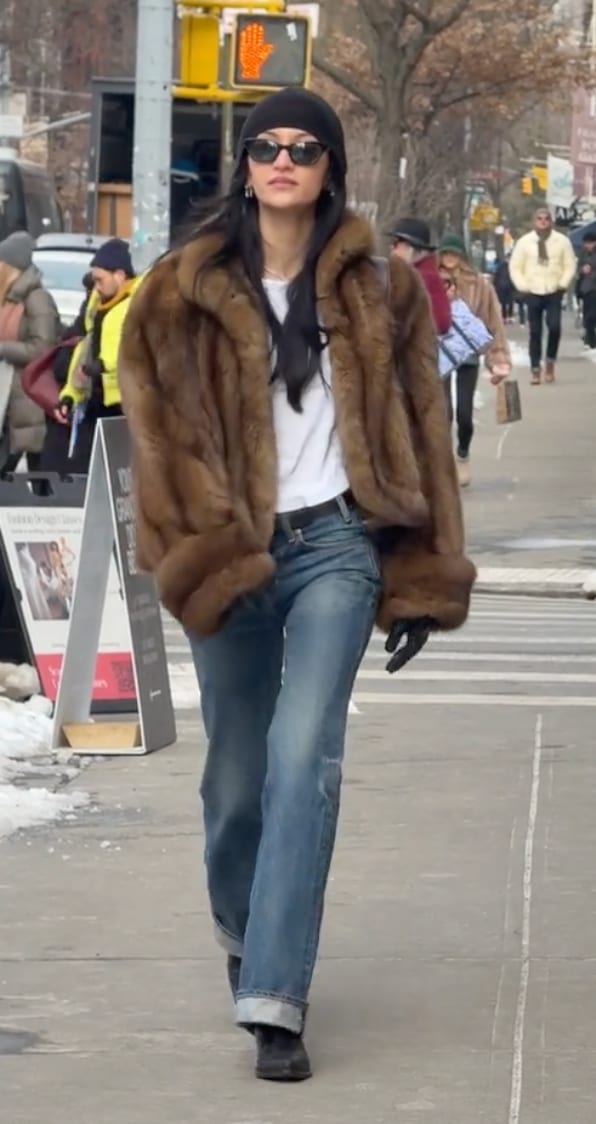 Brown fur coat, white tee, blue wide-leg jeans, black beanie, and cat-eye sunglasses.