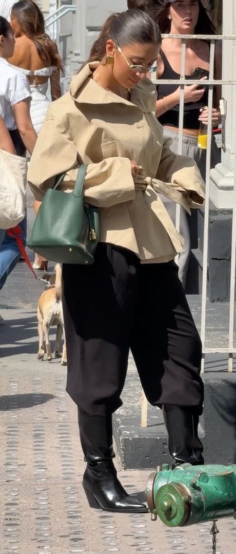 Khaki collared jacket, black pants, black pointed boots, green handbag, and sunglasses.