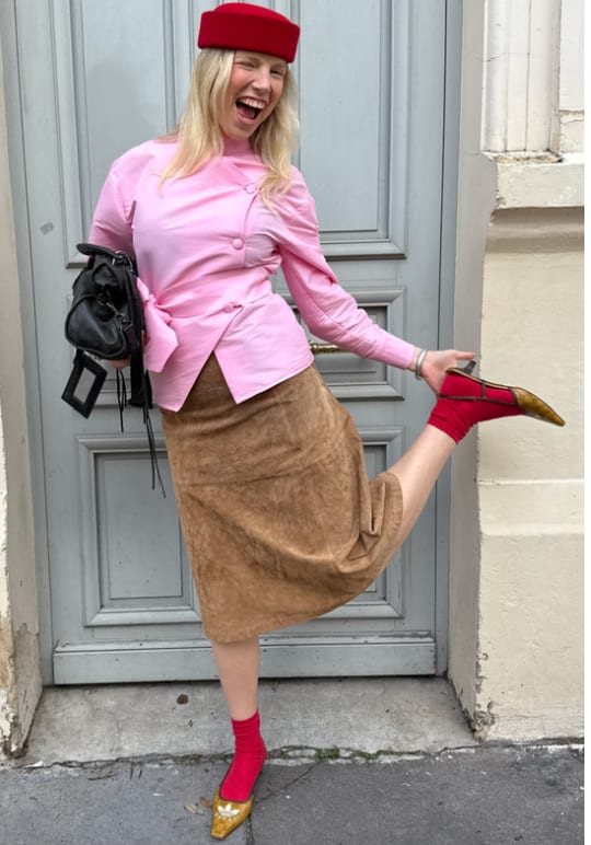 Pink button-up shirt, brown suede skirt, red socks, yellow heels, and a red hat.