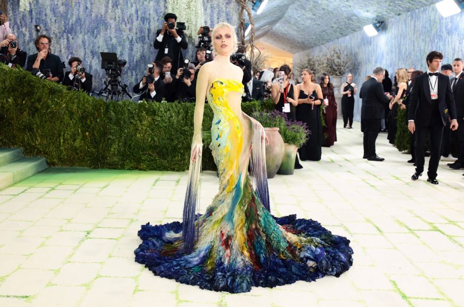 Lady Gaga in a vibrant, sculptural gown with a full, textured blue and yellow skirt.