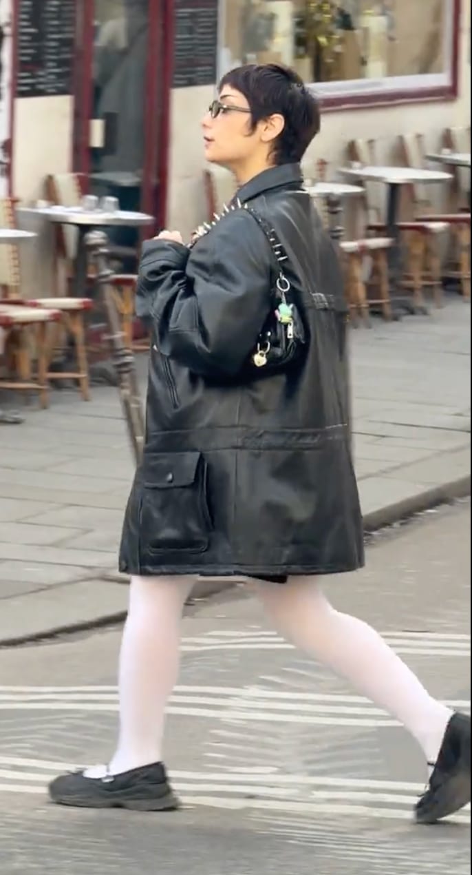 Black studded leather trench coat, white tights, and black Mary Jane shoes.